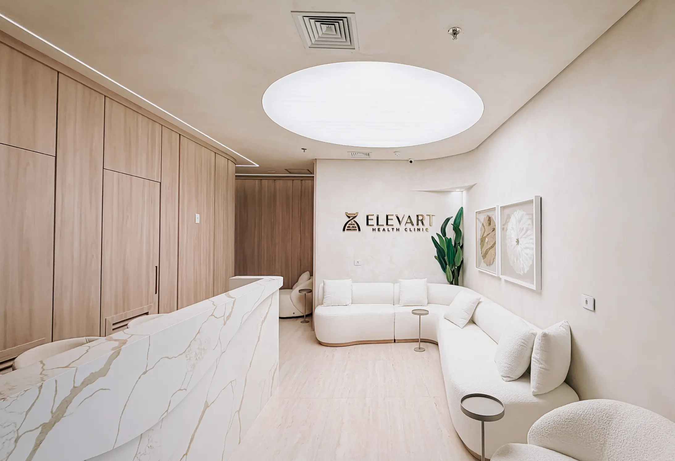 Recepção moderna da Elevart Health Clinic com sofá branco em formato de L, balcão de mármore e parede de madeira clara.